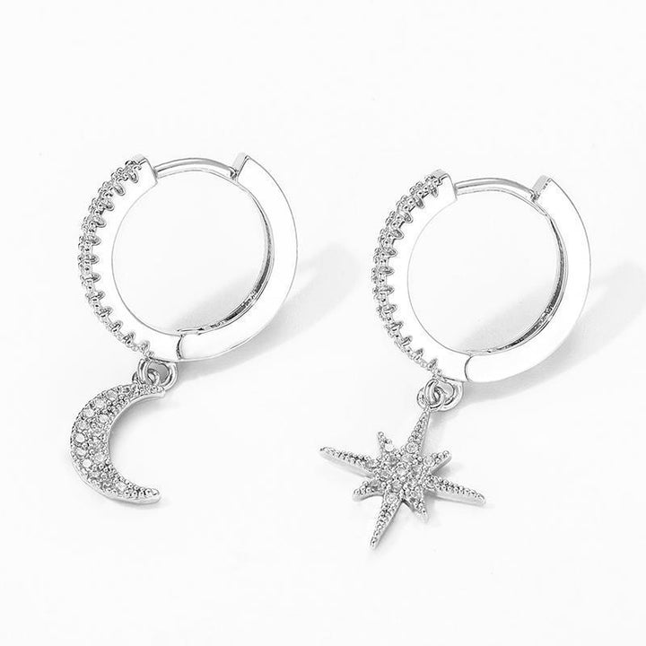 Close-up of sparkling zirconia celestial moon & star drop earrings, elegant gold jewelry for women.