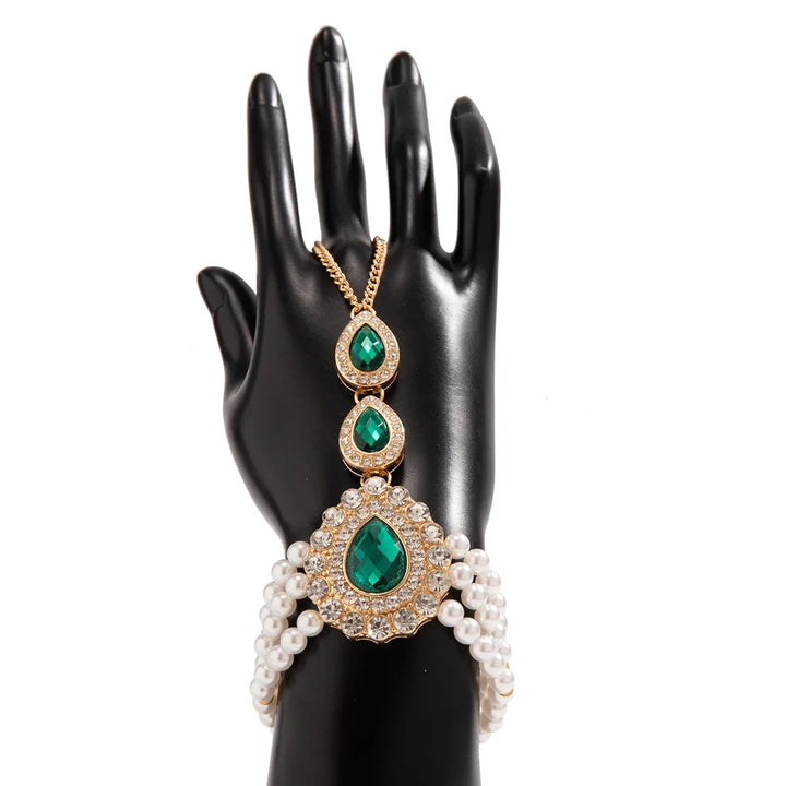 Close-up of a gold pearl and emerald pendant, showcasing the intricate design of this women's statement jewelry set.