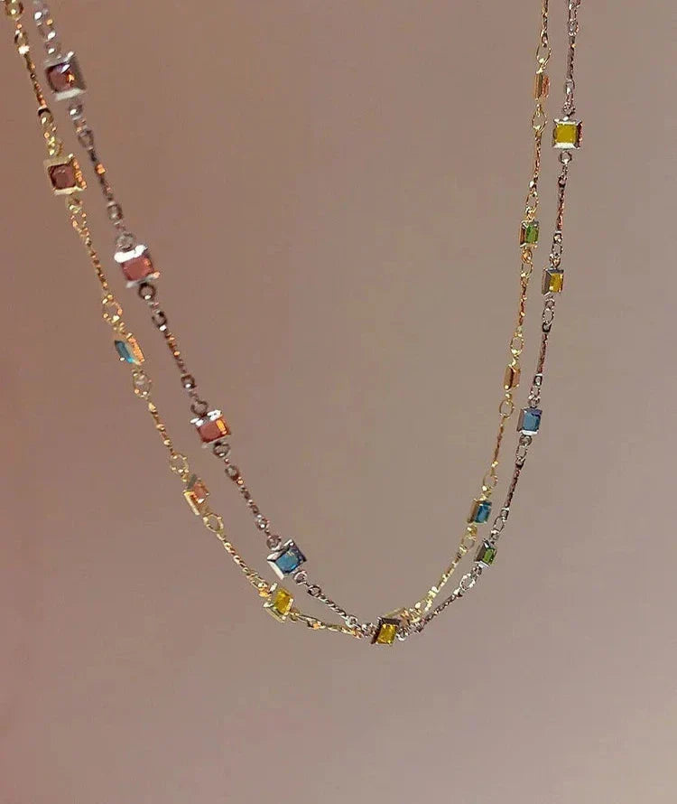 Close-up of a women's gold & silver necklace featuring an array of sparkling colorful stones. Elegant gift for her.