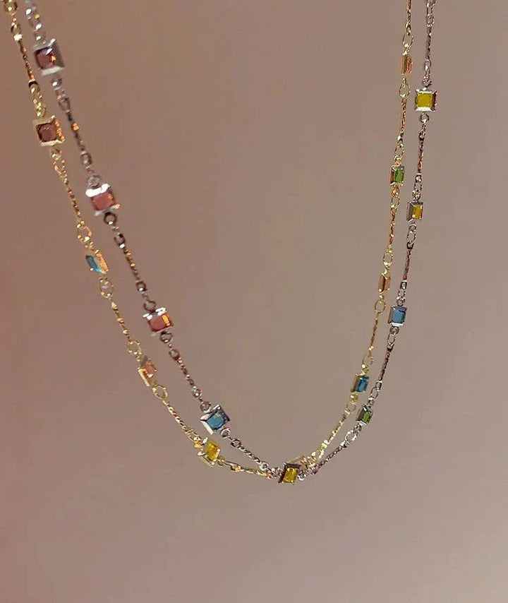 Close-up of a women's gold & silver necklace featuring an array of sparkling colorful stones. Elegant gift for her.