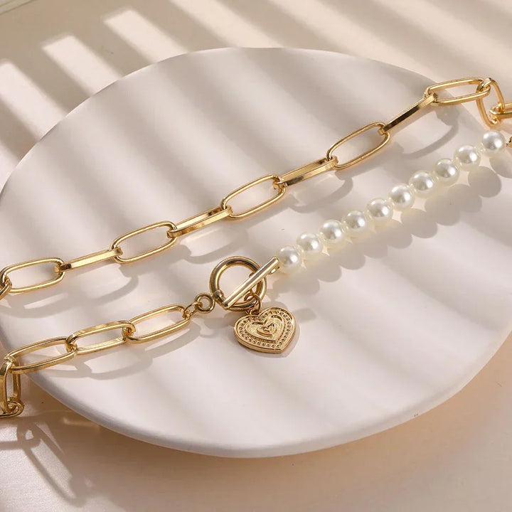 Close-up of a women's golden heart necklace with shimmering pearl accents, elegant fine jewelry.