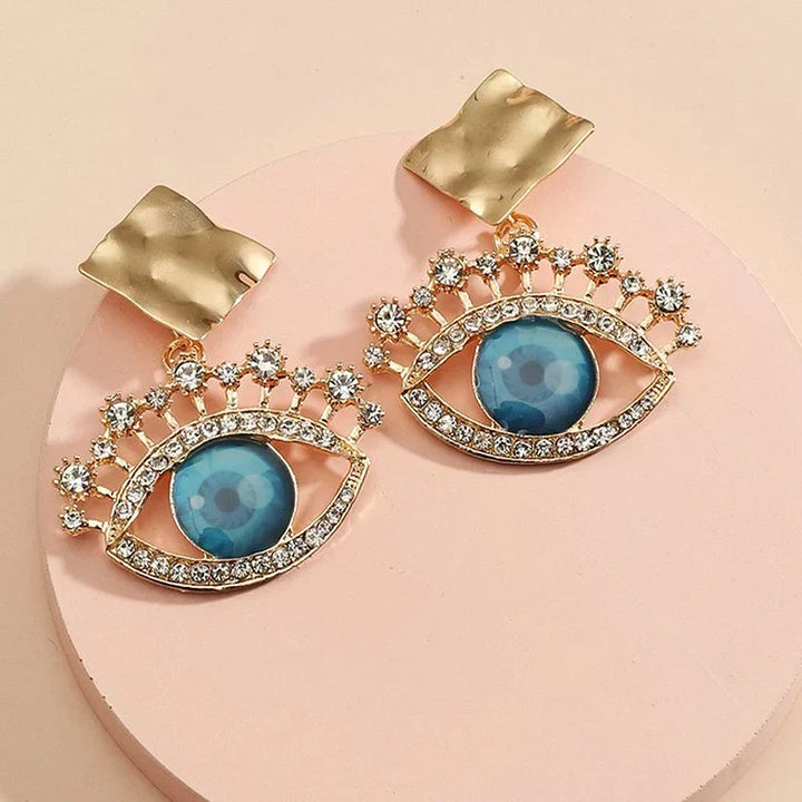 Delicate women's vintage gold evil eye drop earrings with intricate design and sparkling rhinestones.