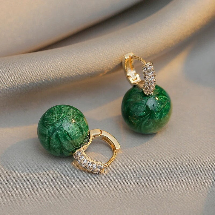 Chic gold-plated drop earrings with captivating green pearls, an essential for women's elegant jewelry collection.
