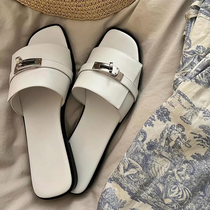 Elegant women's leather square-toe slides with metallic buckle. Chic slip-on summer sandals for casual wear.