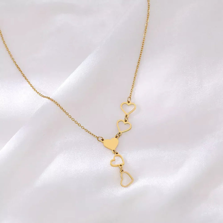 Close-up of a women's linked heart necklace, showcasing polished gold & silver intertwined heart designs.