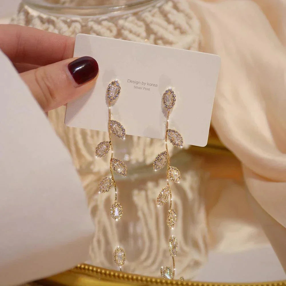 Fashionable women's long dangle earrings with delicate golden leaves. Elegant accessory for any occasion.