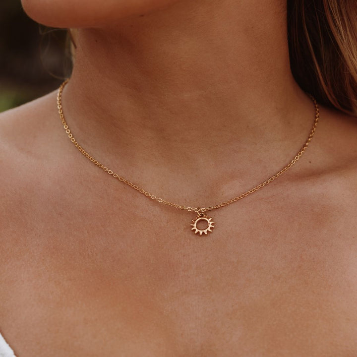 Close-up of a women's radiant sun design pendant on a delicate necklace, elegant celestial jewelry for her.