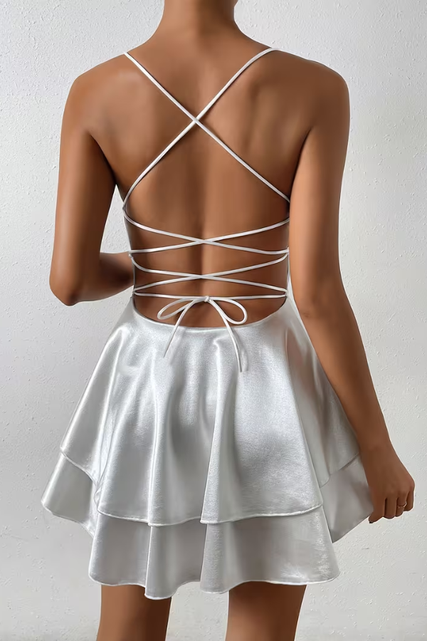 White elegant women's flowing swing dress with open back and pleated details. Ideal for summer parties.