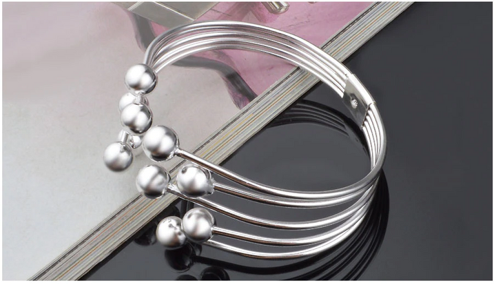 Sophisticated women's wide open cuff bracelet featuring delicate silver beads. A sleek and modern wristband.