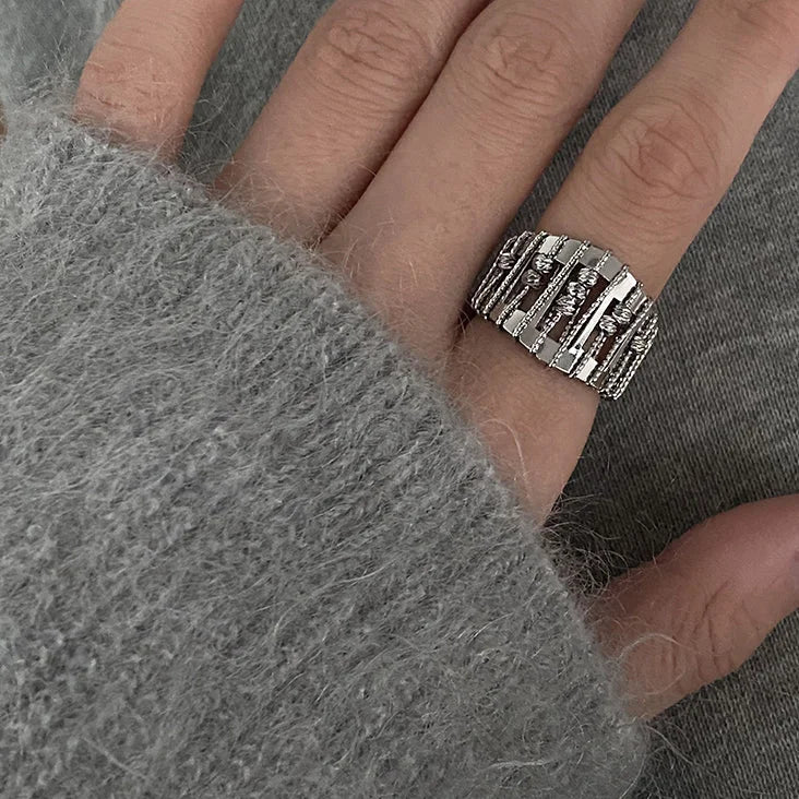 Close-up of a women's elegant openwork pearl ring with intricate silver design & brilliant gemstone accents. Chic jewelry.