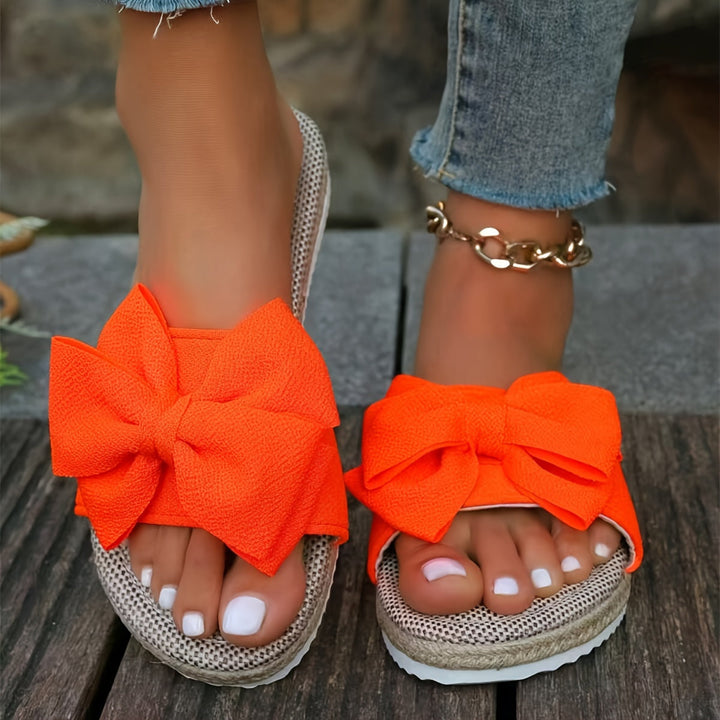 Women's elegant pearl & bow detail flat slide sandals, providing comfortable and chic summer footwear.