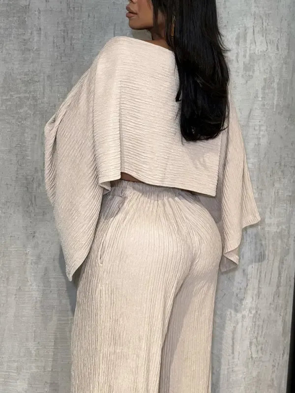 Trendy women's pleated chiffon two-piece outfit with a stylish one-shoulder design and flowing wide-leg pants. Resort ready.