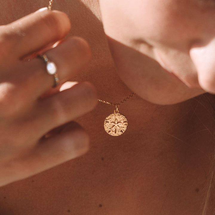 Women's delicate sand dollar pendant, a beautiful piece of coastal gold jewelry. Hypoallergenic and elegant.