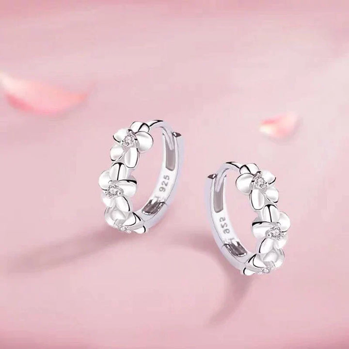 Woman wearing elegant silver floral earrings, adding timeless charm. Delicate women's jewelry, ideal gift.