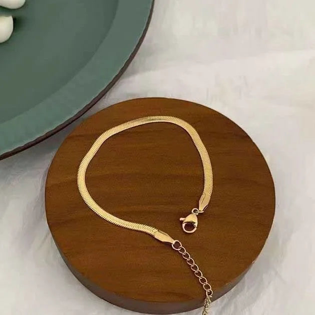 Close-up of a delicate snake chain anklet for women, an elegant gold or silver foot accessory.