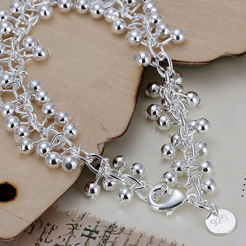 Women's wrist wearing an elegant adjustable silver bead bracelet, perfect for a sophisticated look.