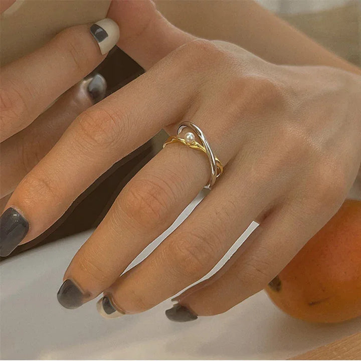 Elegant women's sterling silver crossed ring with a luminous pearl, perfect fashion accessory.