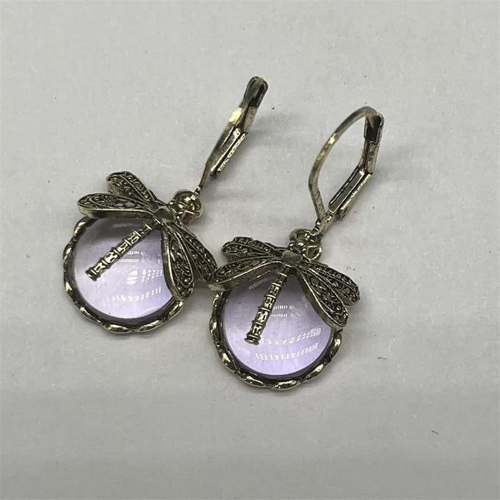 Celestial sterling silver drop earrings featuring a detailed dragonfly and glowing moonstone.