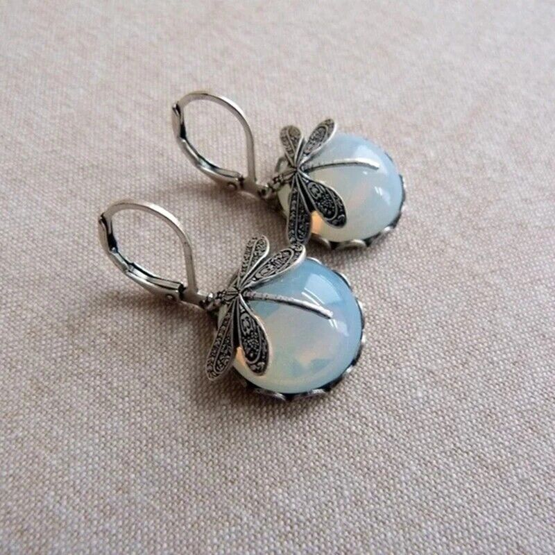 Delicate moonstone drop earrings, sterling silver dragonflies for a whimsical touch.