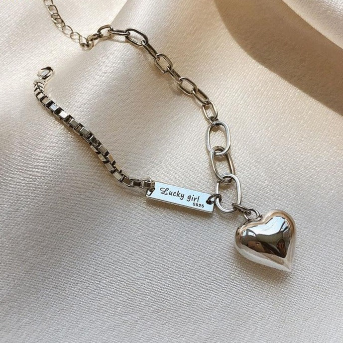 Close-up of a women's sterling silver bracelet featuring a polished heart charm.