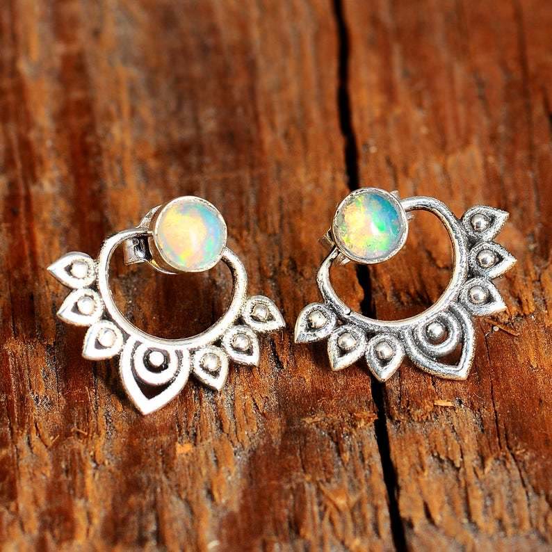 Close-up of delicate women's sterling silver lotus earrings featuring vibrant natural opal inlays.