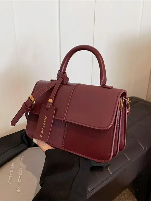 Stylish women's structured top handle bag with a detachable shoulder strap, a versatile and compact fashion accessory.
