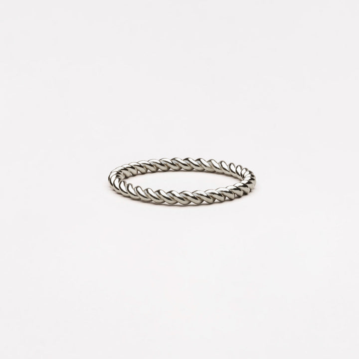 Woman wearing an elegant gold or silver twisted symbolic ring, highlighting its connection & beauty.