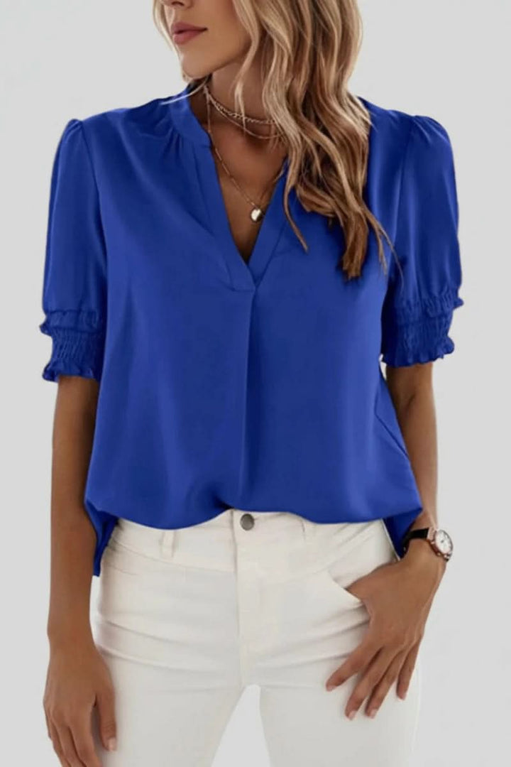 Detail of an elegant women's V-neck blouse, highlighting the chic short puff sleeves and soft fabric.