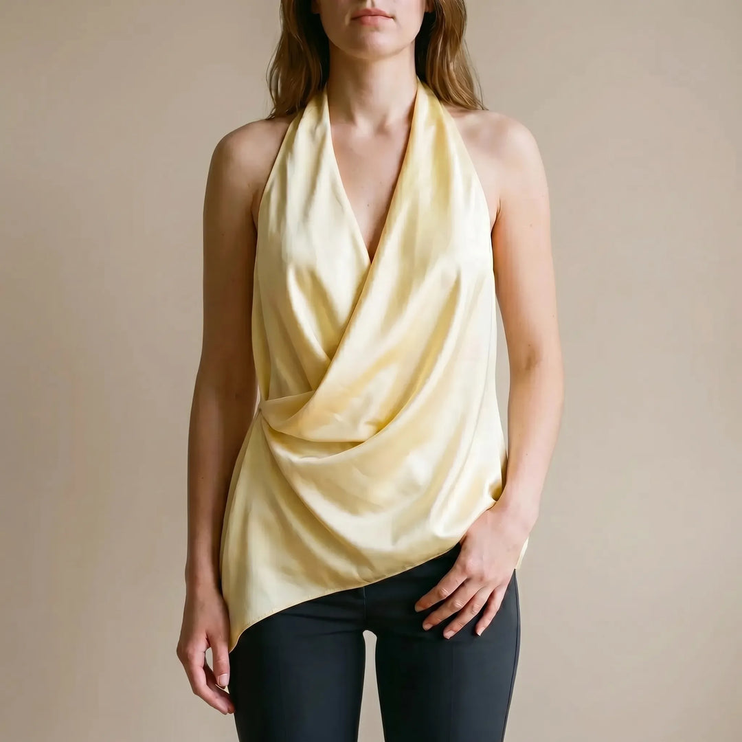 Elegant yellow draped halter top for women with an asymmetrical hem. Chic sleeveless design, perfect for summer or evening.