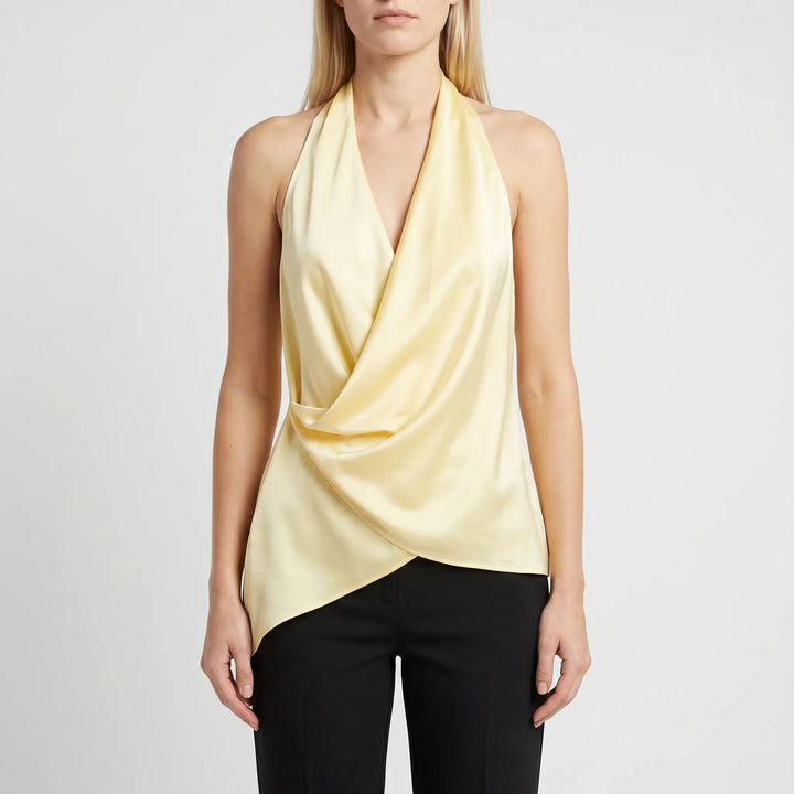 Chic women's yellow draped halter blouse featuring an asymmetrical hem & open back. Modern sleeveless style, versatile fashion.