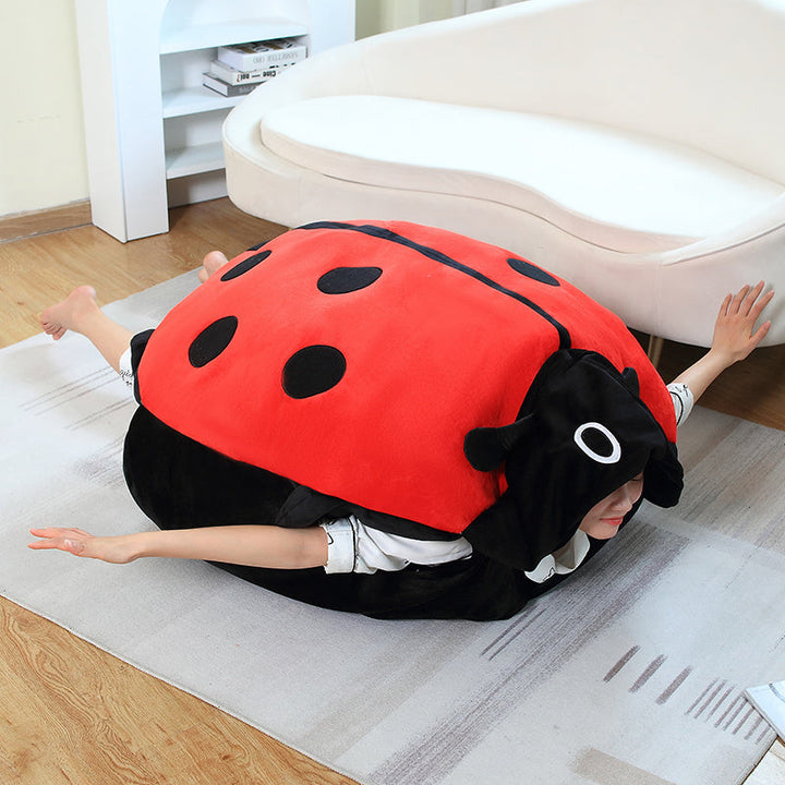 Child happily wearing a giant ladybug plush pillow, enjoying its oversized, cozy comfort as a unique animal toy.