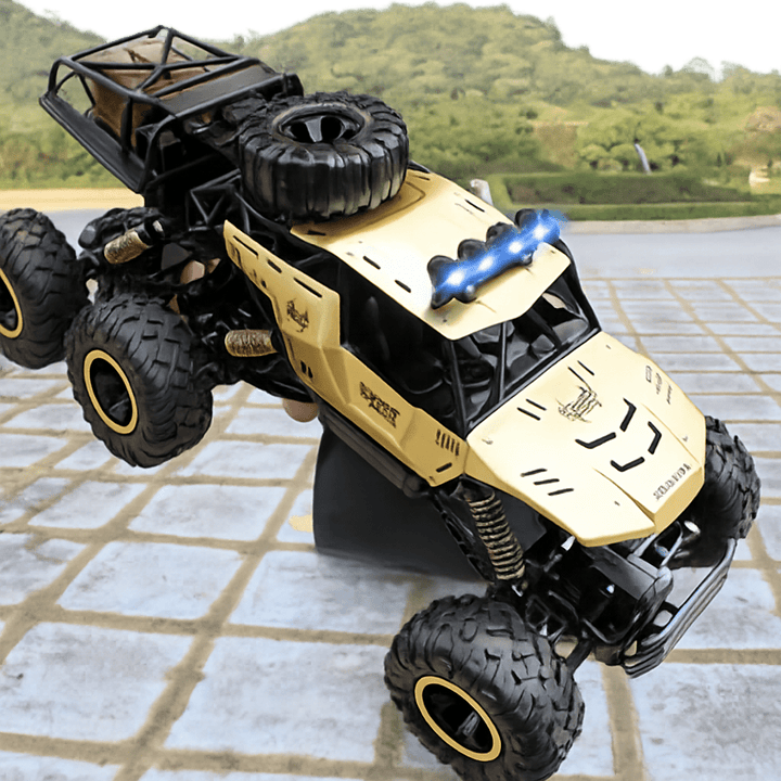 Gold & black all-terrain 6x6 RC monster truck, conquering a rugged off-road path with powerful wheels.