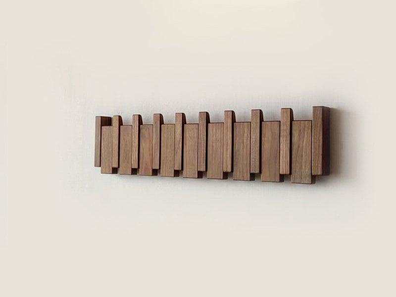 Modern wooden coat rack with innovative folding hooks. Wall-mounted entryway storage for decluttering hallways.