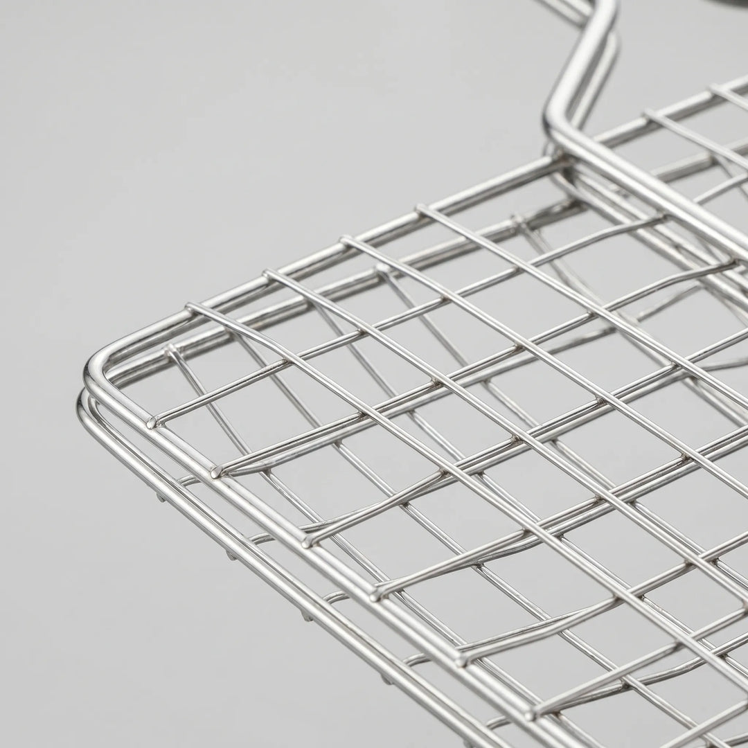Durable metal hinged grill basket, an essential BBQ accessory for grilling various meats and vegetables outdoors.