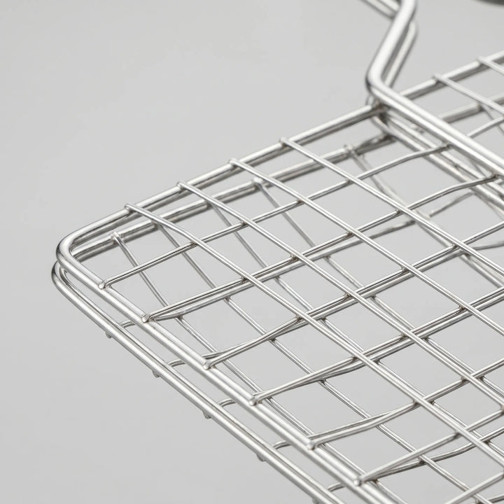 Durable metal hinged grill basket, an essential BBQ accessory for grilling various meats and vegetables outdoors.