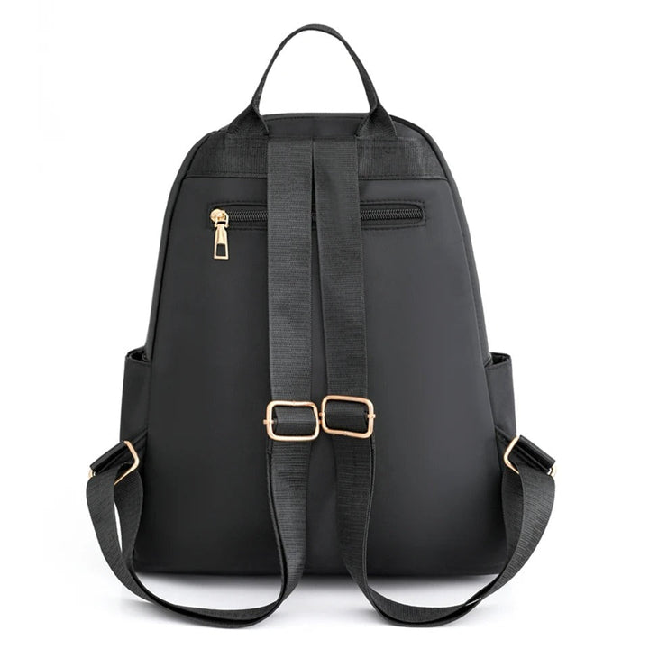 Detail of the zipper and adjustable straps on a black lightweight water-resistant women's backpack.