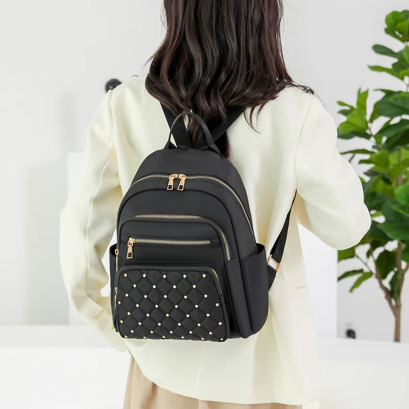 Two women's lightweight water-resistant nylon backpacks, khaki and black, displayed together.
