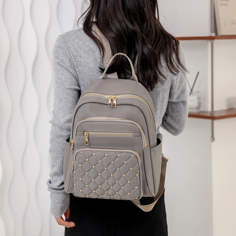 Lifestyle shot of a black water-resistant nylon backpack for women amidst urban environment.