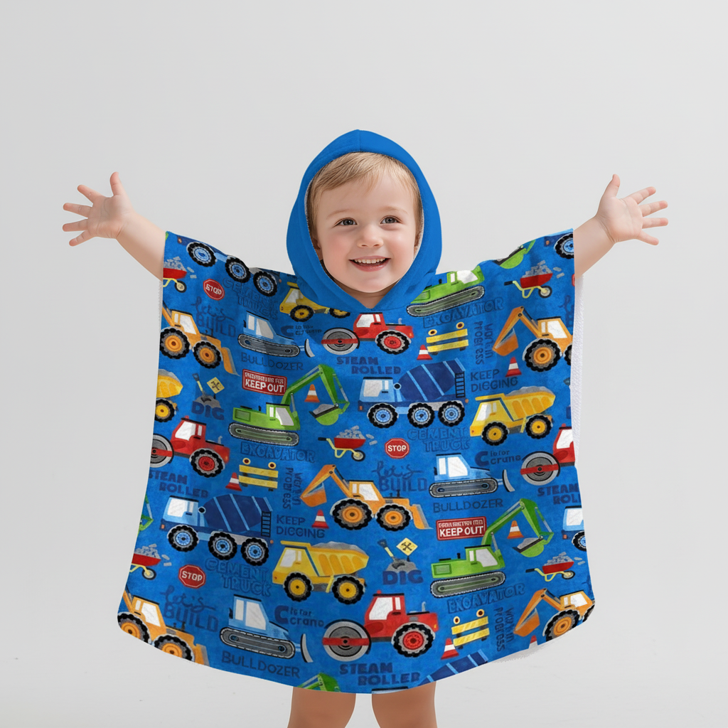 Child wearing a construction print hooded poncho, side view, ideal for rain and outdoor play.