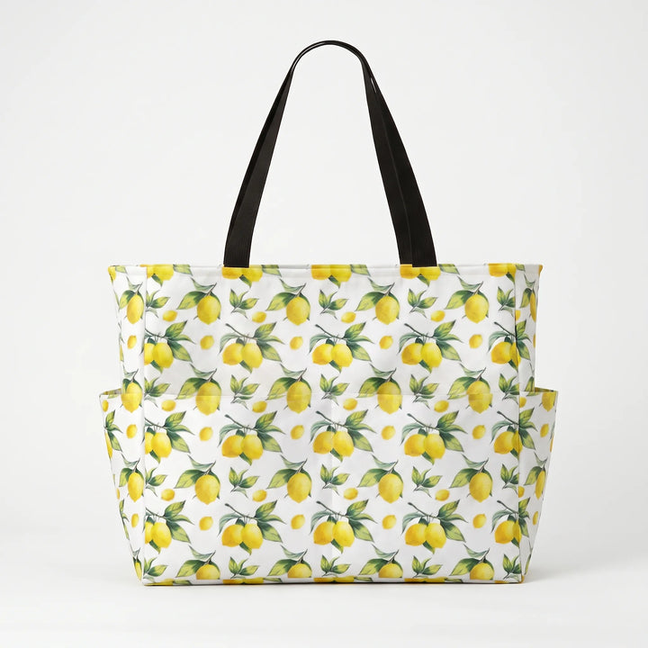 Woman carrying a stylish large tropical lemon print beach tote bag, perfect for summer outfits.