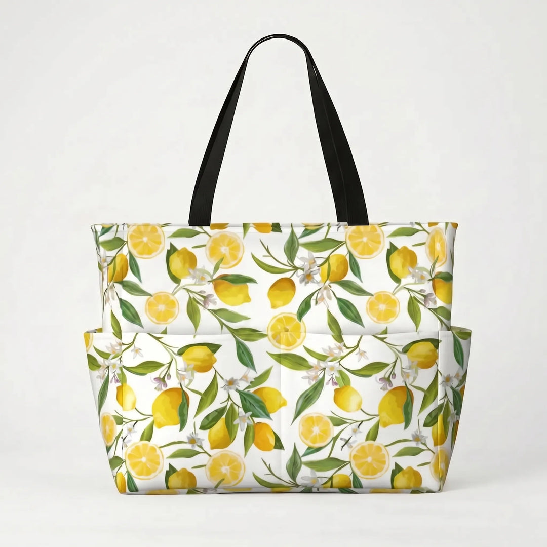Tropical lemon print large beach tote bag on sand, ready for a relaxing vacation day by the ocean.