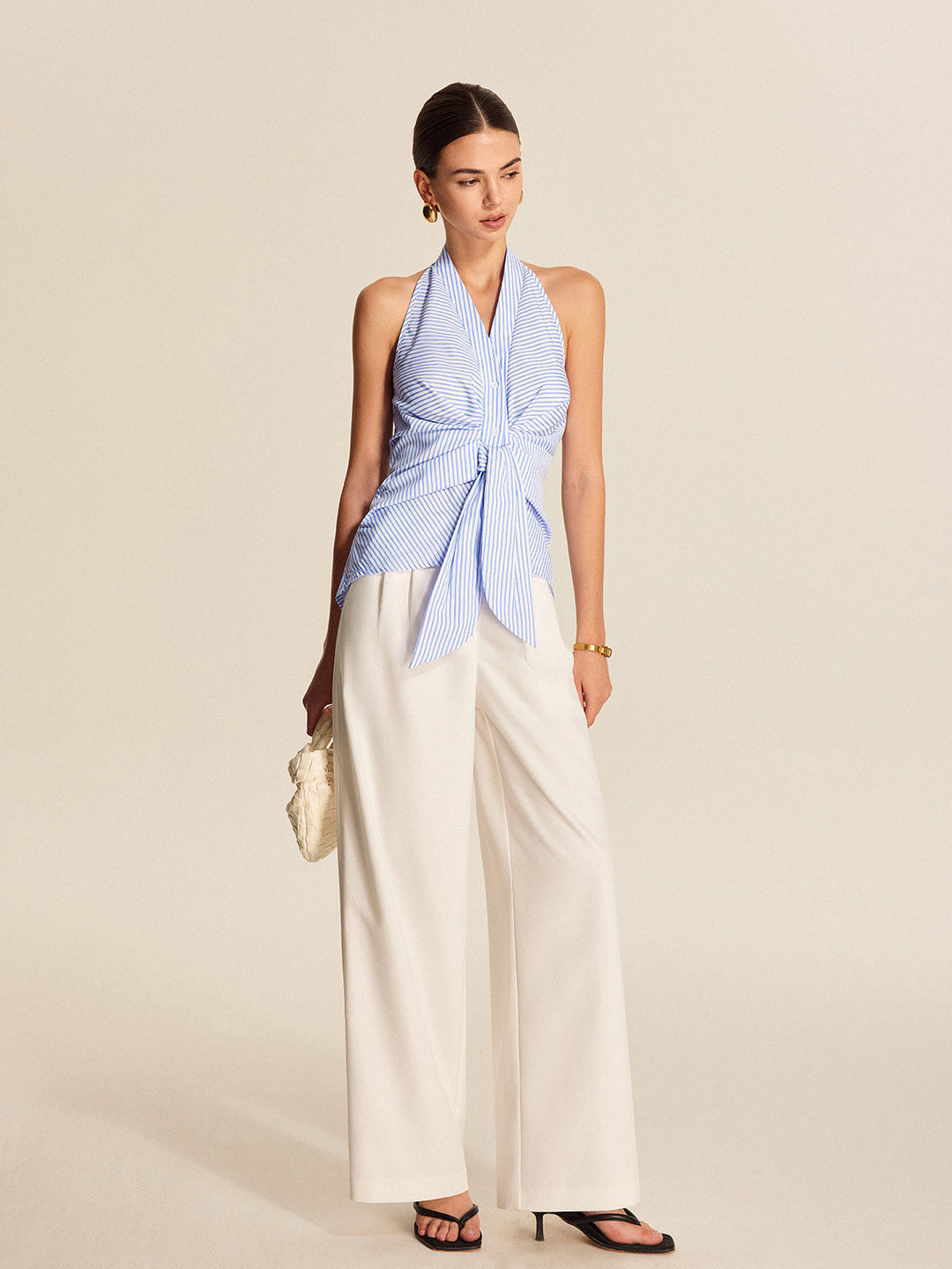 Stylish women's sleeveless striped halter blouse, featuring a trendy tie front. Ideal for office wear or a casual chic look.