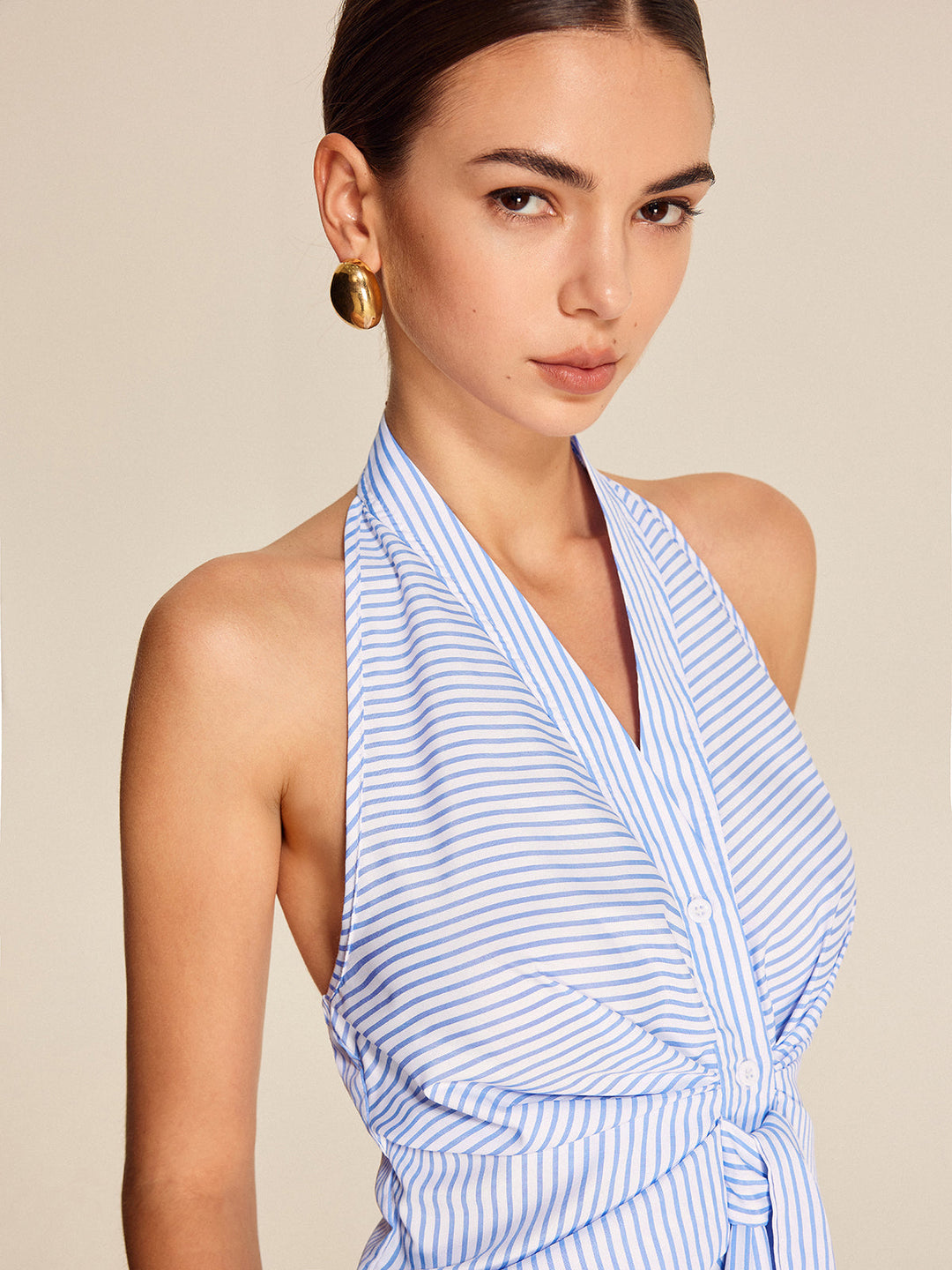 Chic women's light blue striped halter blouse with a trendy tie front. A sleeveless design for modern workwear fashion.
