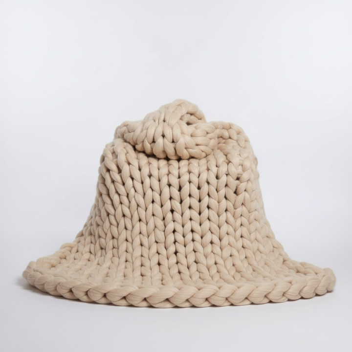A ball of super thick Wooluxe knitting yarn next to a measuring tape, showing its voluminous size.