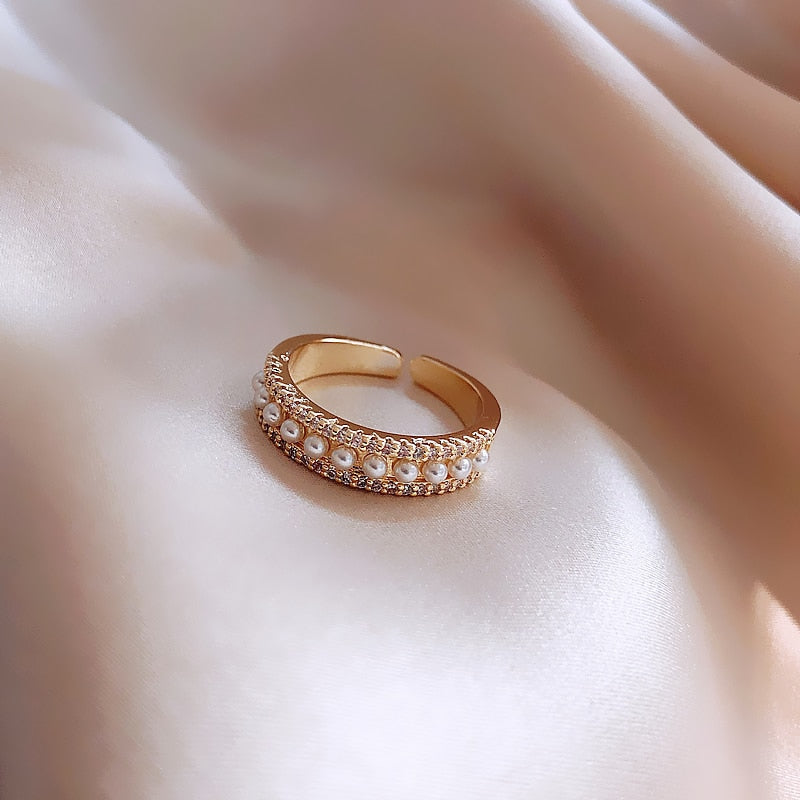 Close-up of a women's elegant gold ring with a radiant white pearl. A beautiful luxury accessory for special moments.