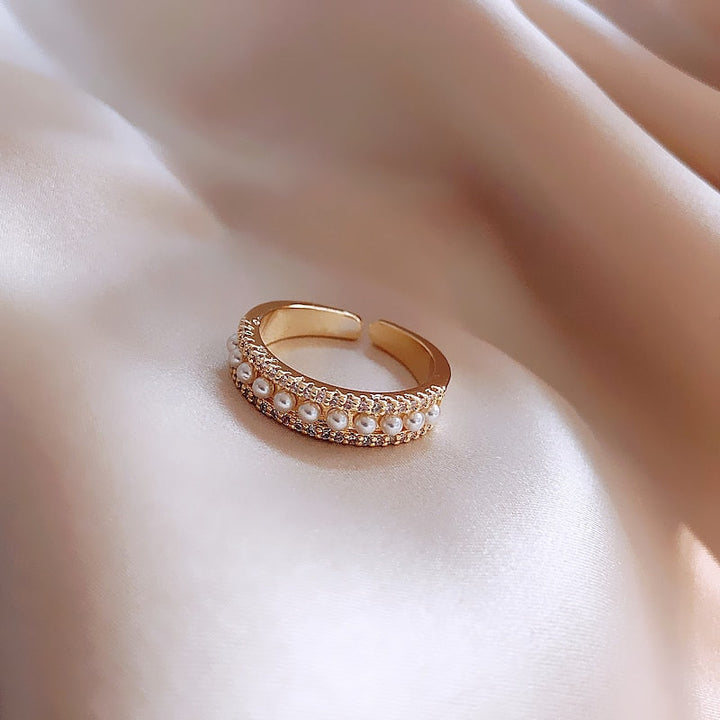 Close-up of a women's elegant gold ring with a radiant white pearl. A beautiful luxury accessory for special moments.