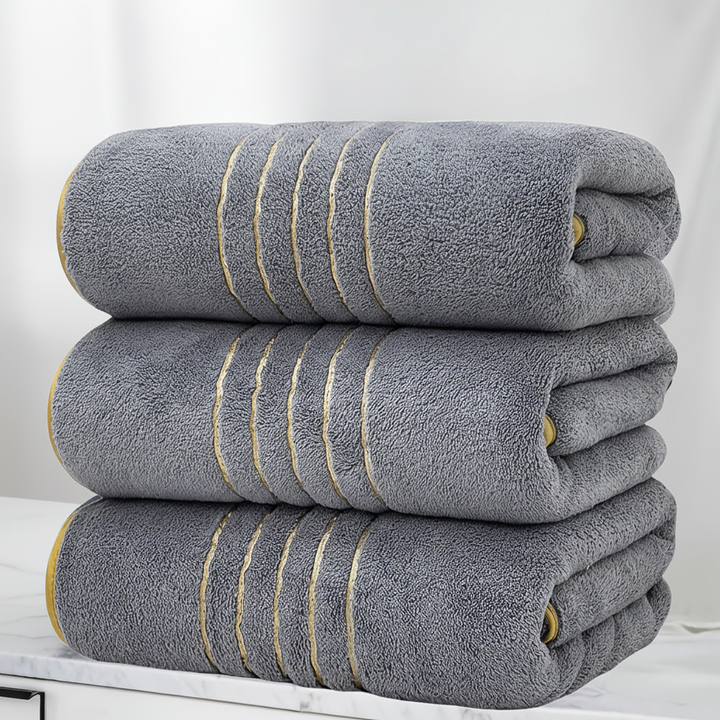 A person drying off with a large white and grey striped LuxuryWrap microfiber bath towel, showing absorbency.