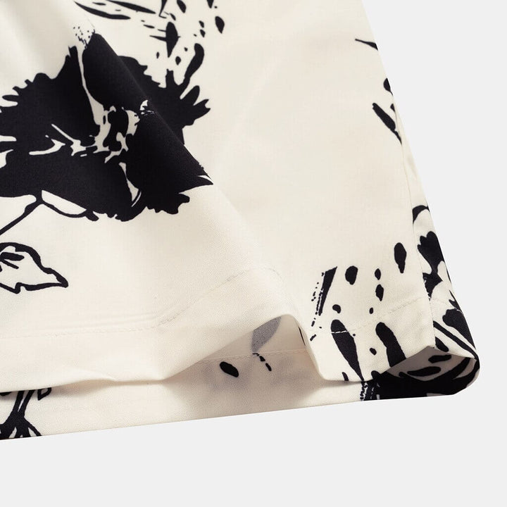 A stack of folded men's AlohaVibes tropical print short sleeve shirts, showcasing various summer fashion patterns.
