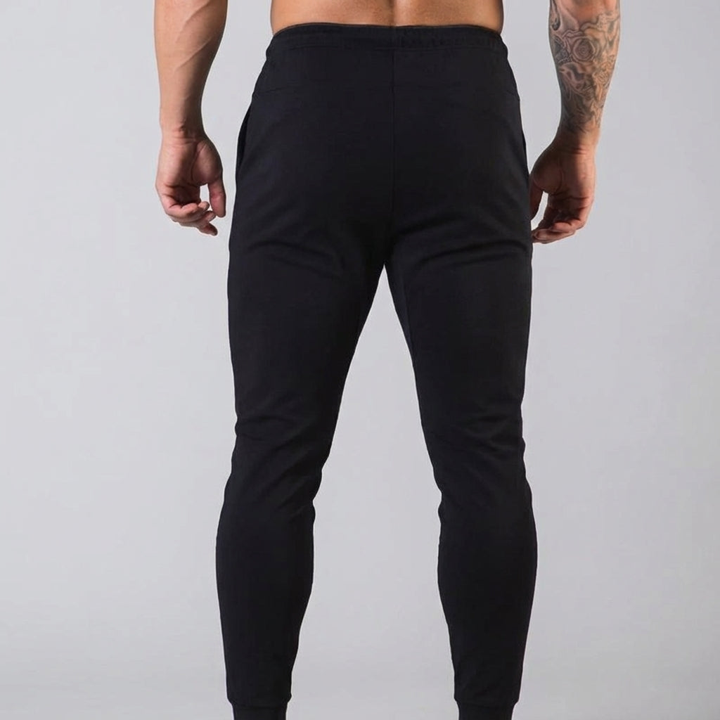 Closeup of men's tapered athletic trousers, highlighting the elastic waist and cotton blend texture.