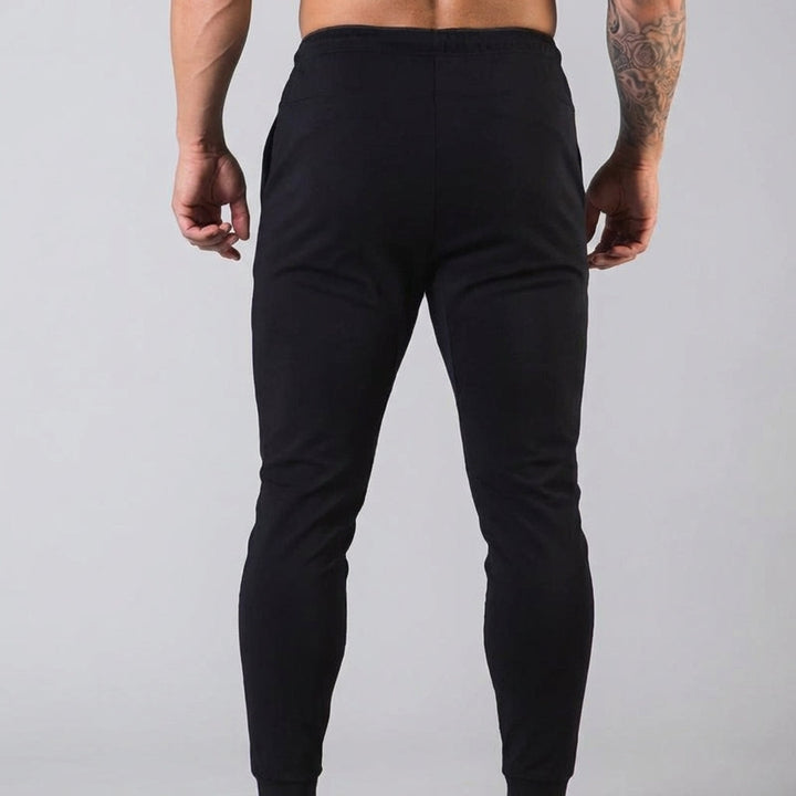 Closeup of men's tapered athletic trousers, highlighting the elastic waist and cotton blend texture.